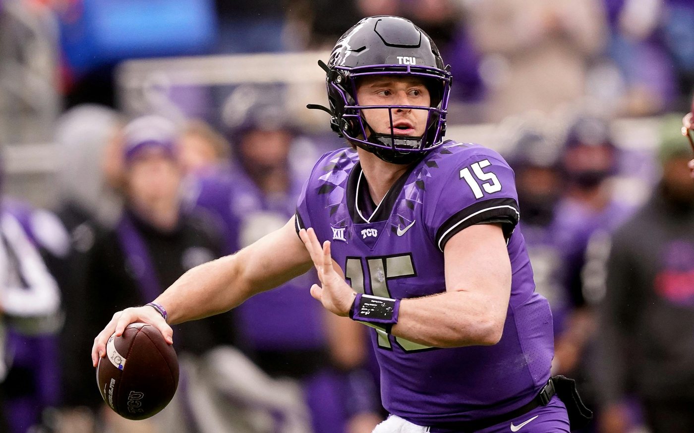 Max Duggan in TCU purple, helmet on, rolling out with the ball in his right hand